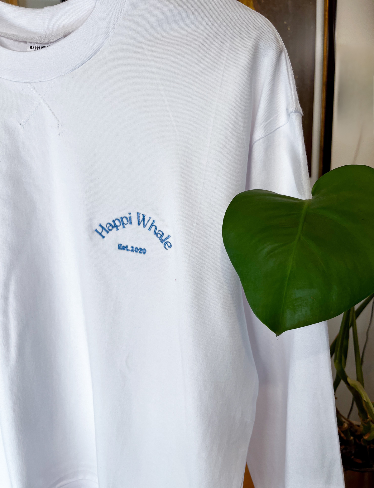 Close-up of the sky-blue Happi Whale embroidery on the white Boyfriend Crew