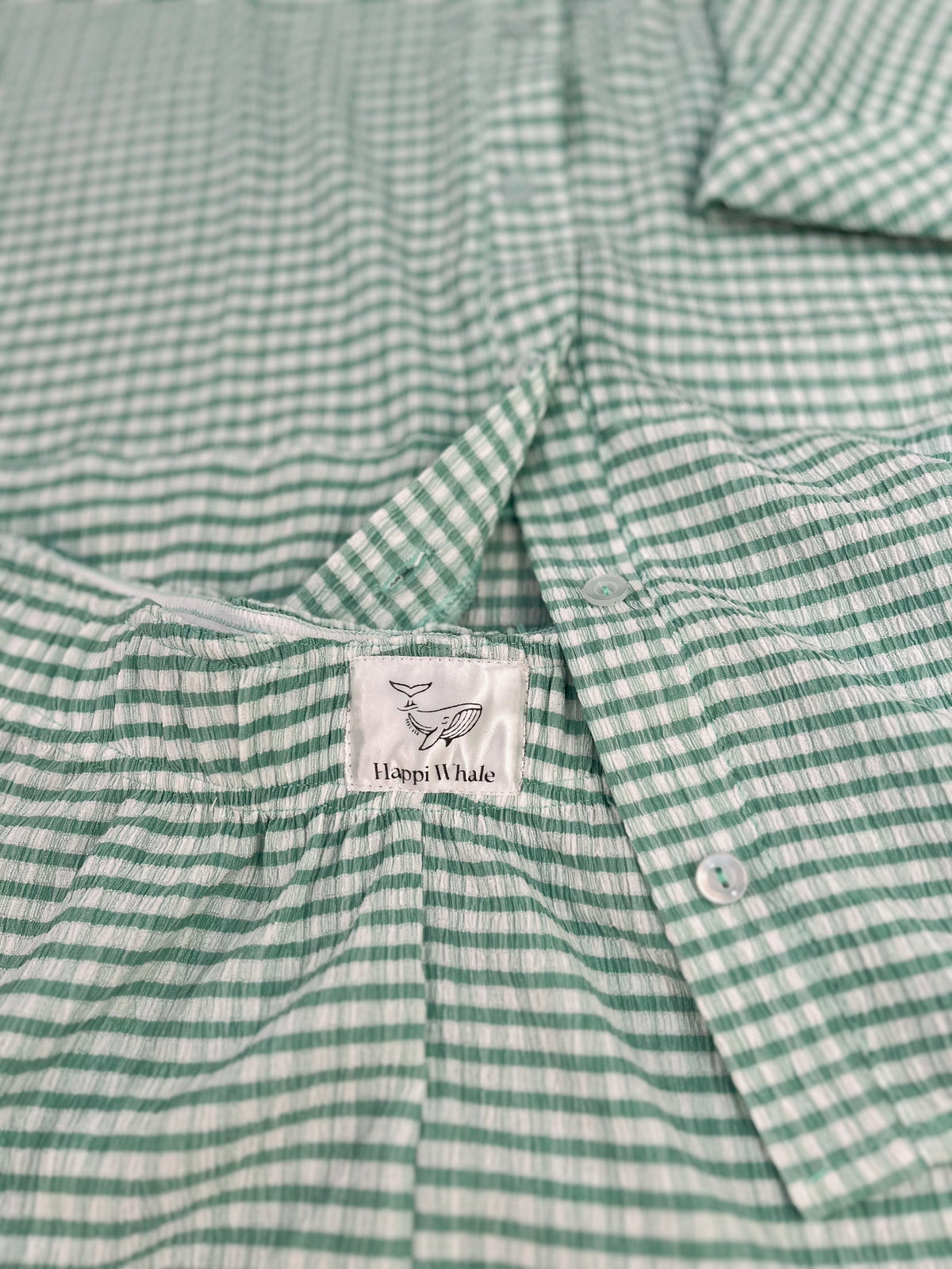Close-up of green gingham bubble cotton with the Happi Whale label