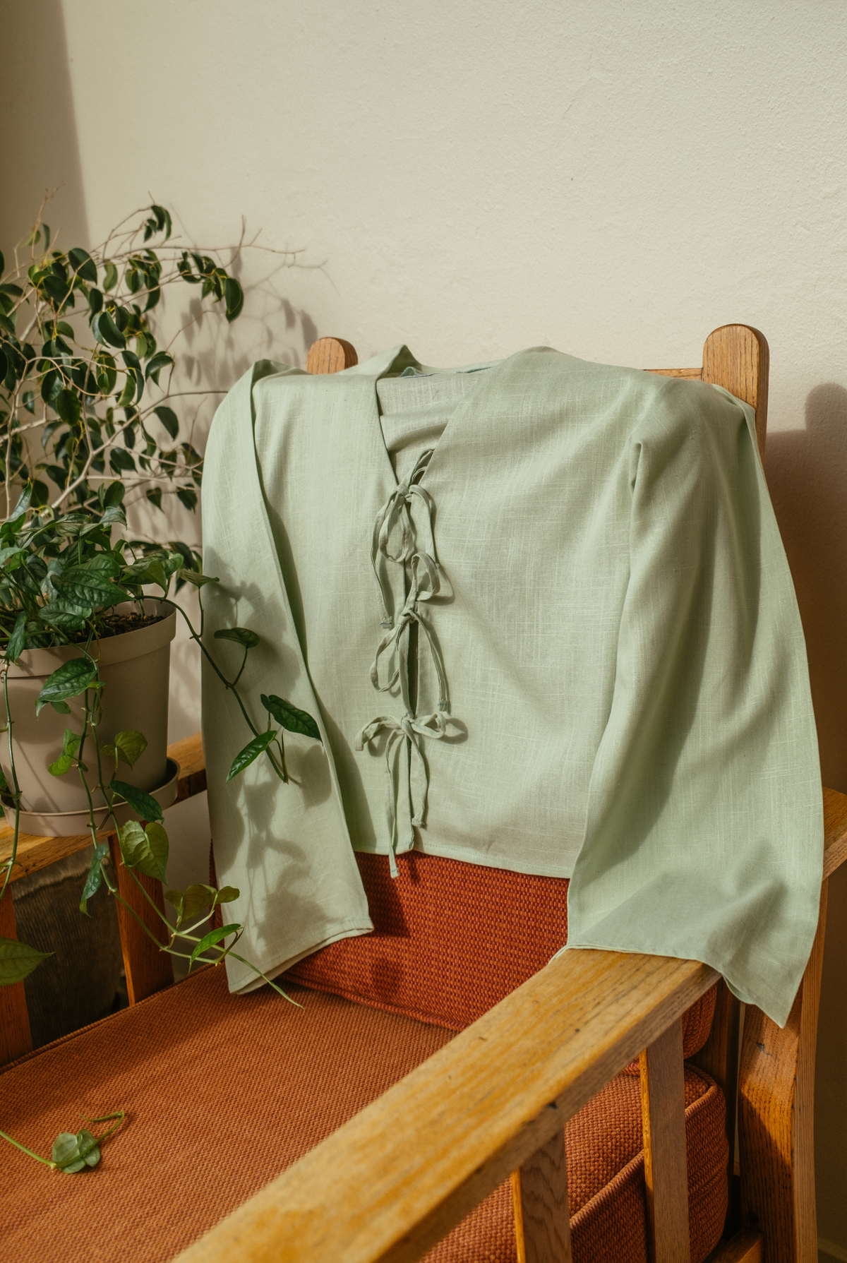Back view of the sage green Cove Top draped over a wooden chair