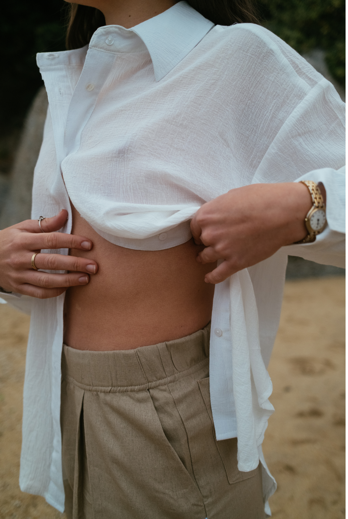 Close-up of the white Hillie's Breeze Shirt worn open over high-waisted linen shorts
