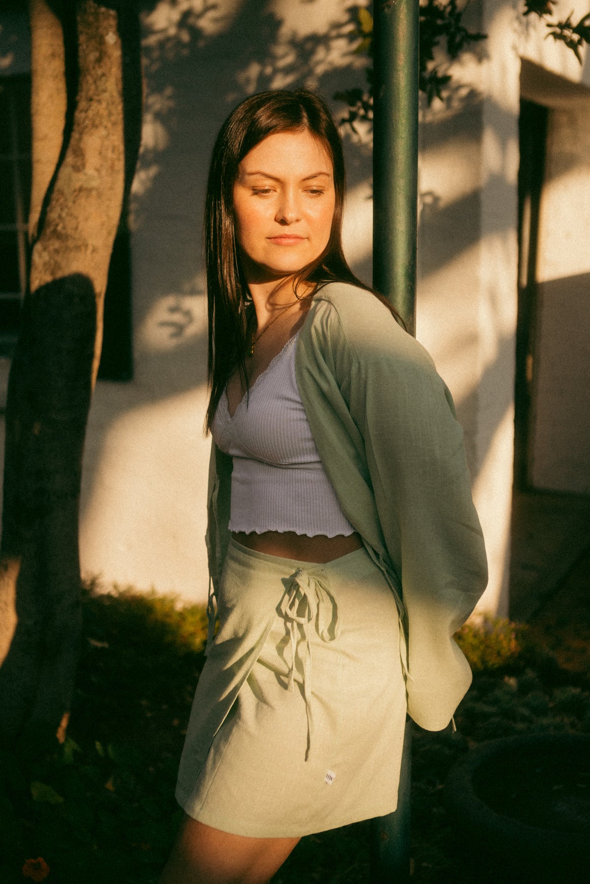 Woman in a garden wearing the sage green Matcha Linen Wrap Skirt with a matching jacket