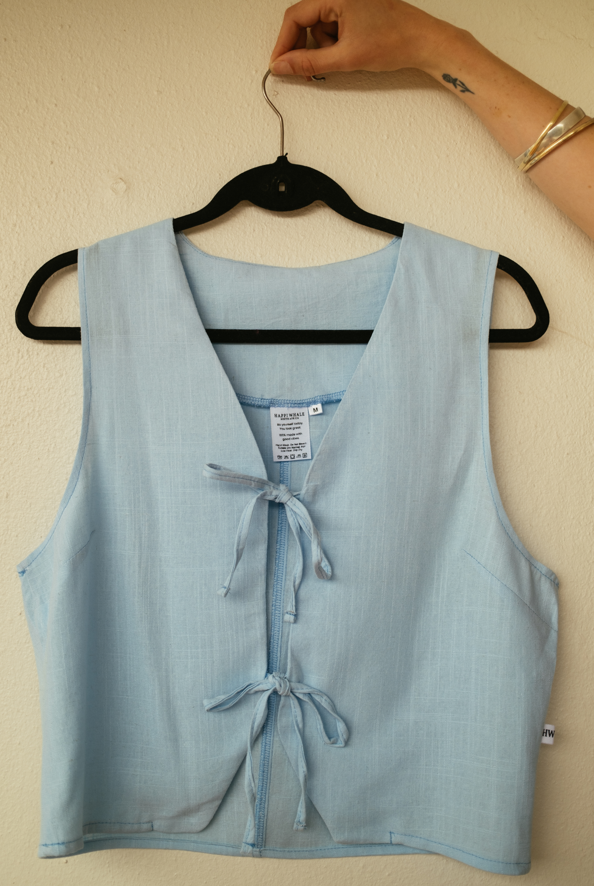 Sky Tie Vest held up on a hanger, showing its fully lined interior and ties